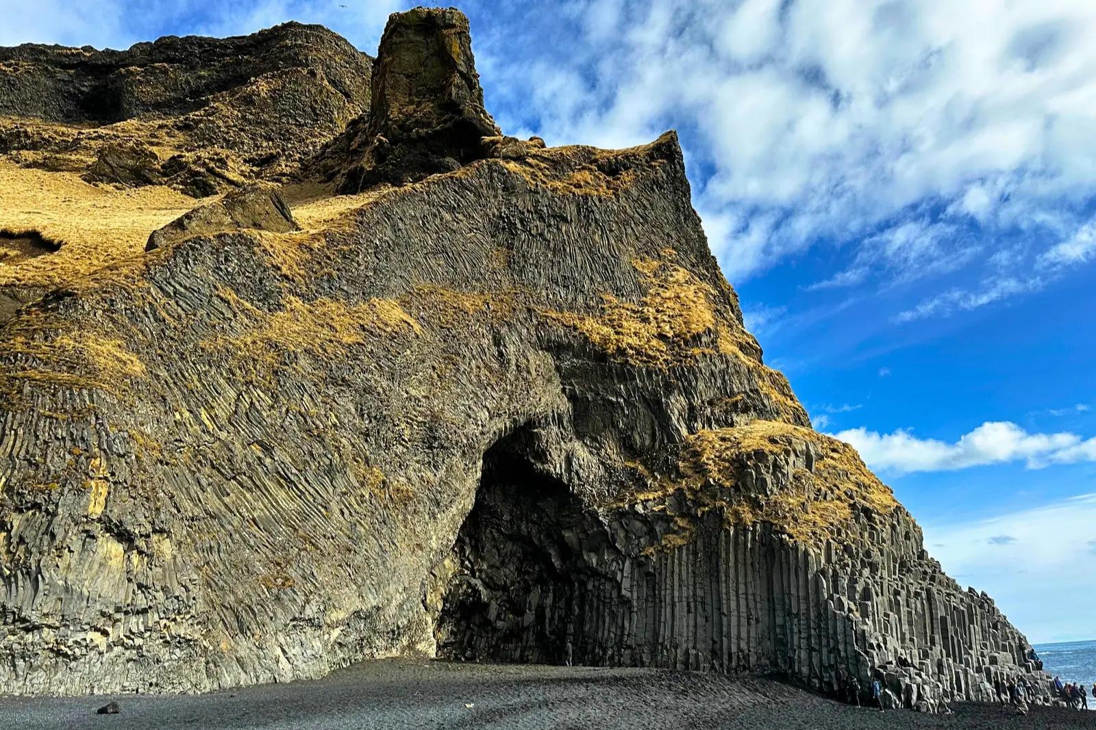 A sea cave in a cliff of hexagonal basalt columns above the black sand beach at Reynisfjara.