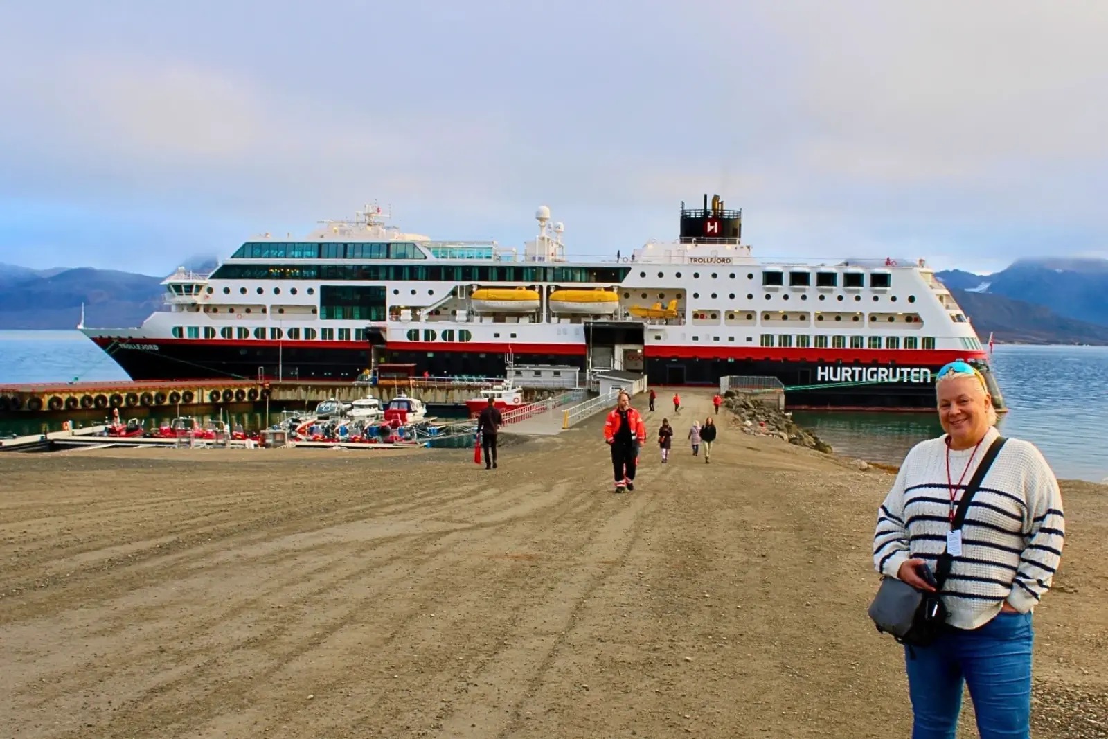 Erika Commisso on the gravel pier with the Trollfjord docked behind her.