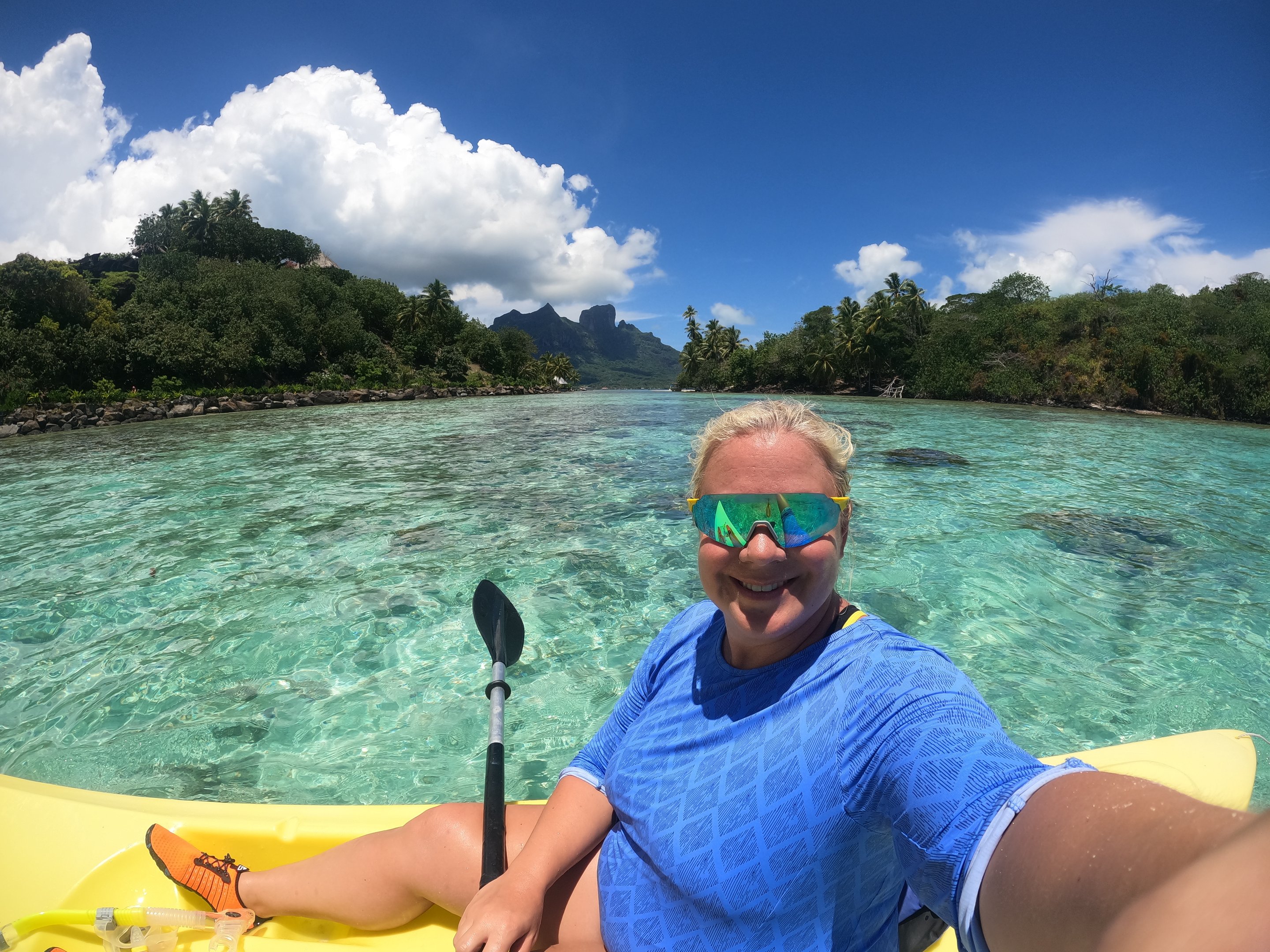 Kayaking across a clear turquoise lagoon in French Polynesia on a warm-weather expedition day.