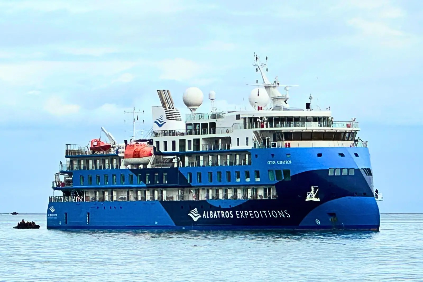 Ocean Albatros at anchor in blue Albatros Expeditions livery, with a Zodiac alongside.