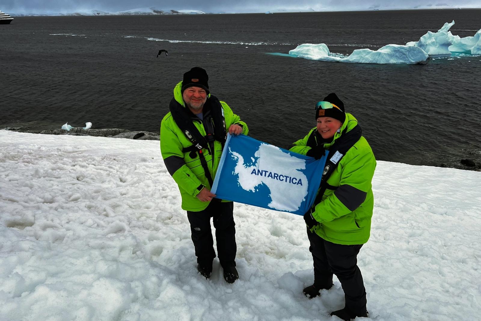 Chris and Erika holding an Antarctic flag at Portal Point