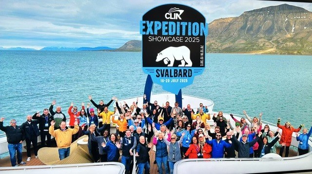 Summit participants waving on the bow of an expedition ship under a CLIA Expedition Showcase 2025 Svalbard graphic.