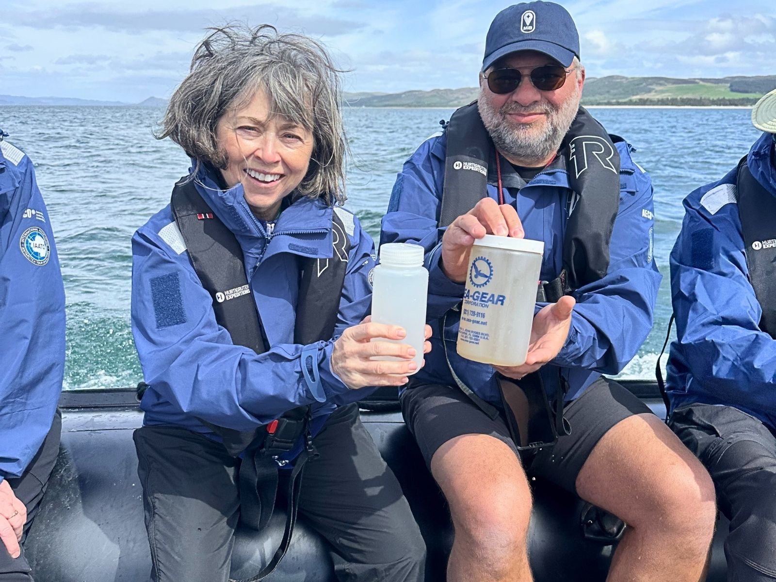 Two researchers on a small boat collecting ocean water samples for marine conservation research