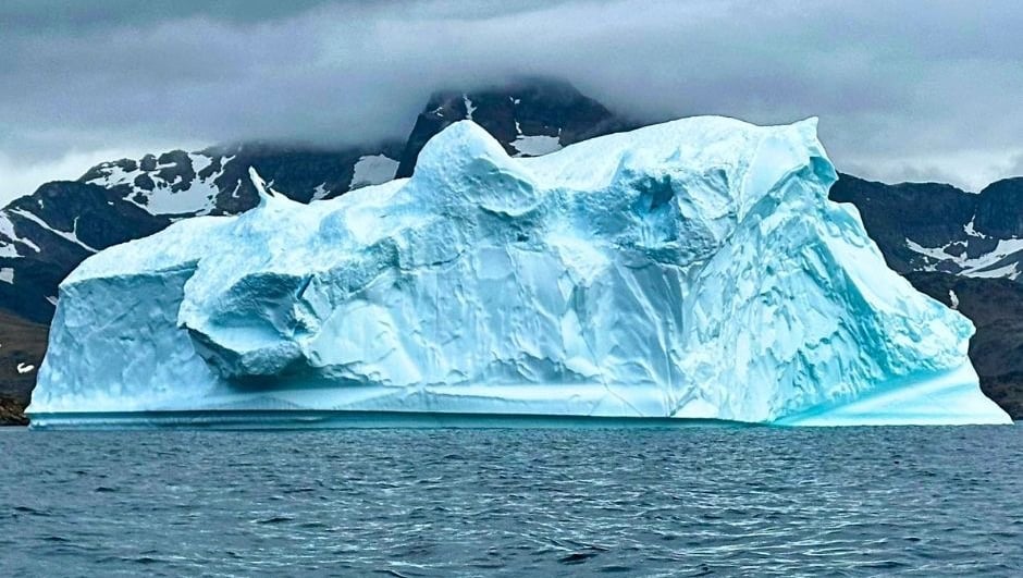 Colossal grounded tabular icebergs towering over an expedition Zodiac in the deep waters of Scoresby Sund, East Greenland.