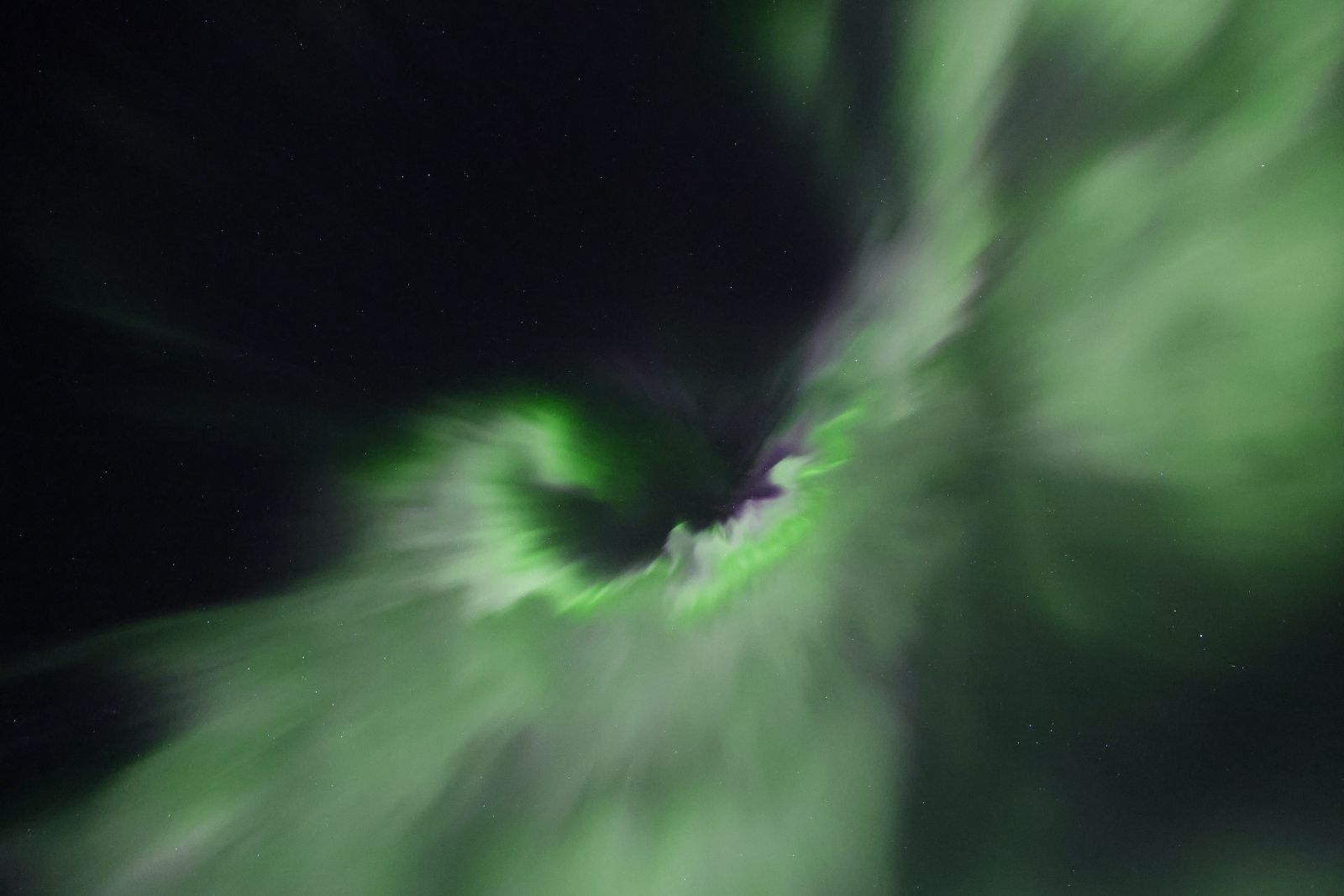 The aurora forming a corona directly overhead, green and violet radiating from a central point.