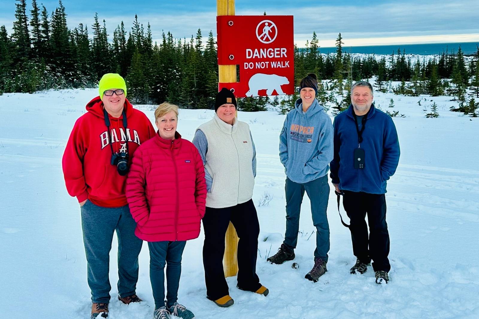 Our group at the polar bear warning sign, with Hudson Bay still open water behind us.