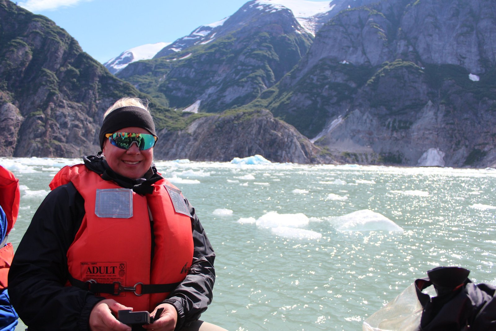 Erika Commisso in a life jacket aboard a Zodiac on brash-ice-strewn water below snow-streaked Alaskan mountains.